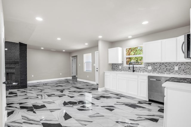 kitchen with sink, white cabinetry, backsplash, stainless steel appliances, and a brick fireplace