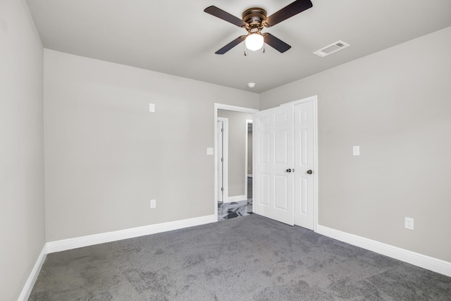 empty room featuring ceiling fan and dark colored carpet