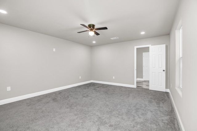 unfurnished room with ceiling fan and dark colored carpet