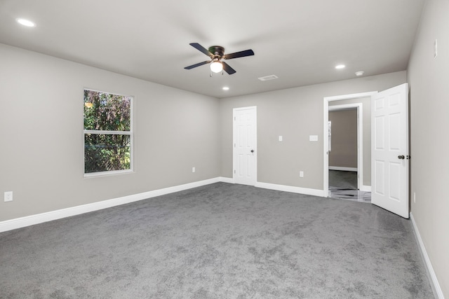 unfurnished bedroom with ceiling fan and dark colored carpet