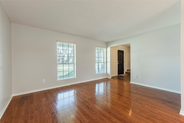 unfurnished room with a textured ceiling and dark hardwood / wood-style floors