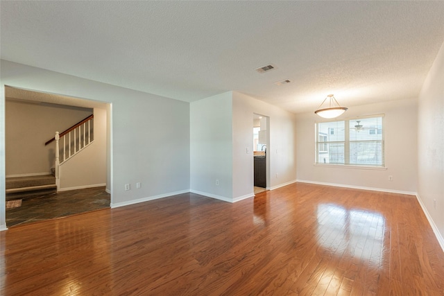 empty room with a textured ceiling and dark hardwood / wood-style floors