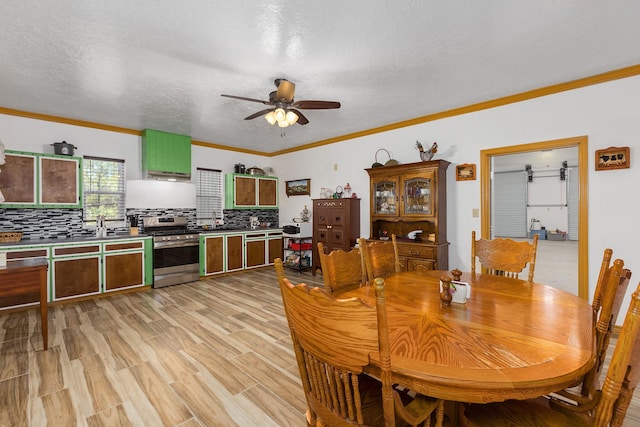 dining area featuring ceiling fan, light hardwood / wood-style floors, a textured ceiling, and ornamental molding