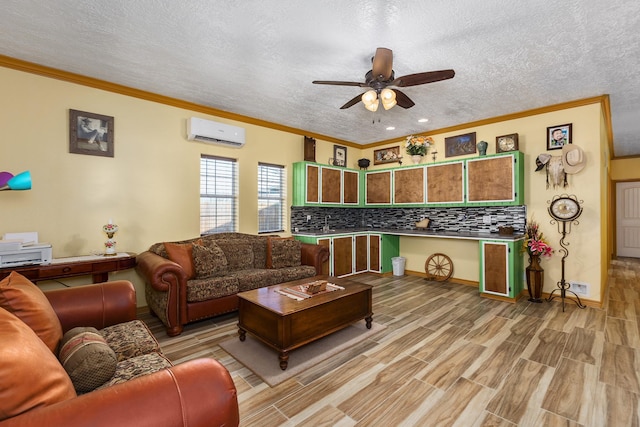 living room with crown molding, ceiling fan, a textured ceiling, light hardwood / wood-style floors, and a wall unit AC