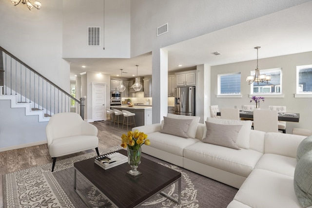 living room with a wealth of natural light, dark hardwood / wood-style flooring, and a notable chandelier