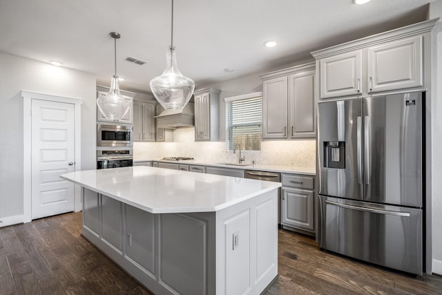 kitchen with gray cabinets, a center island, dark hardwood / wood-style flooring, and appliances with stainless steel finishes