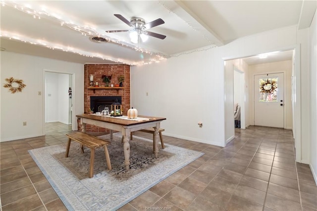 dining space with beamed ceiling, ceiling fan, and a fireplace