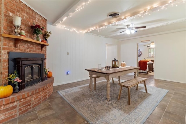 tiled dining area featuring ceiling fan and a brick fireplace