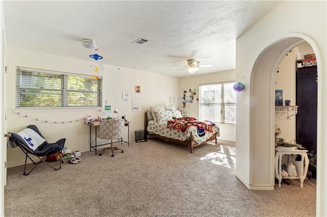 bedroom with a textured ceiling, light colored carpet, and ceiling fan