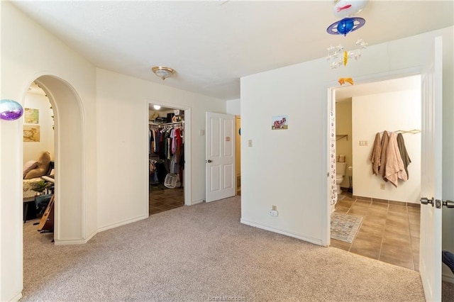 unfurnished bedroom featuring a walk in closet, light carpet, and a closet