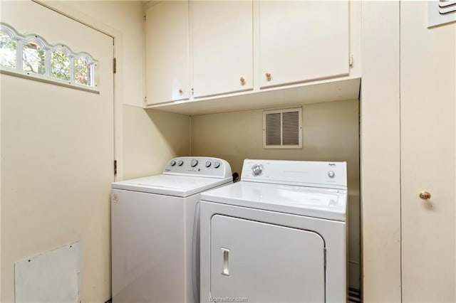 clothes washing area with cabinets and separate washer and dryer