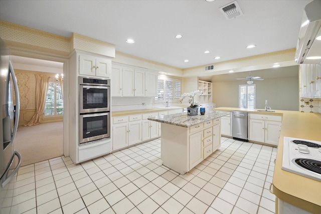 kitchen featuring a center island, light carpet, crown molding, appliances with stainless steel finishes, and white cabinetry