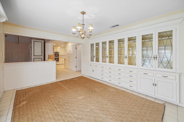 unfurnished dining area with light tile patterned floors, an inviting chandelier, and crown molding