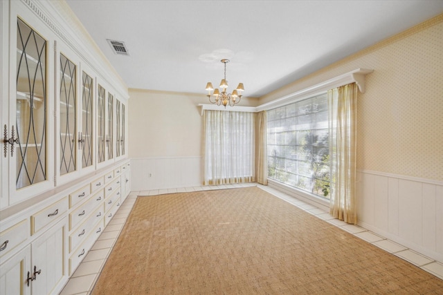 unfurnished dining area with light tile patterned floors, crown molding, and a chandelier