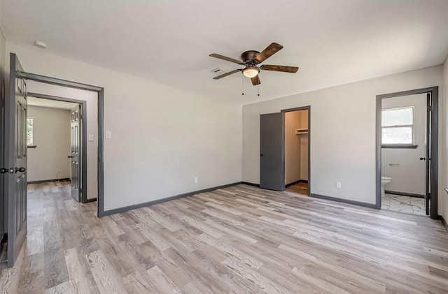 unfurnished bedroom with a walk in closet, ceiling fan, light hardwood / wood-style flooring, connected bathroom, and a closet