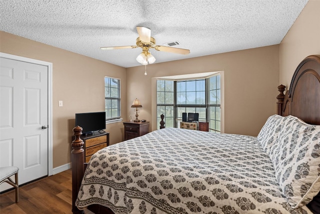 bedroom with ceiling fan, dark hardwood / wood-style floors, and a textured ceiling