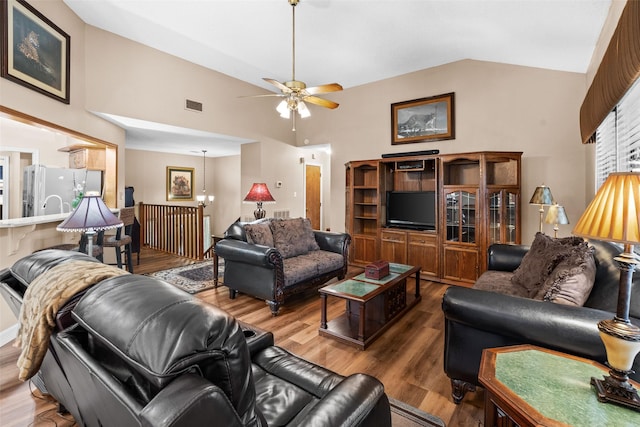 living room with lofted ceiling, ceiling fan with notable chandelier, and hardwood / wood-style floors