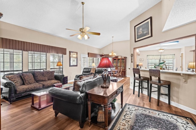 living room with plenty of natural light, ceiling fan with notable chandelier, and hardwood / wood-style floors