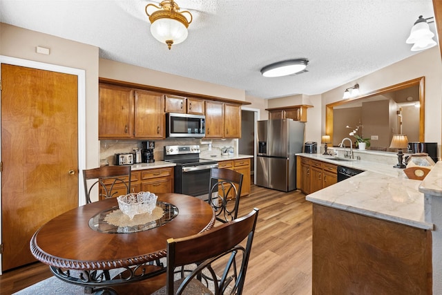 kitchen featuring backsplash, kitchen peninsula, sink, appliances with stainless steel finishes, and a textured ceiling