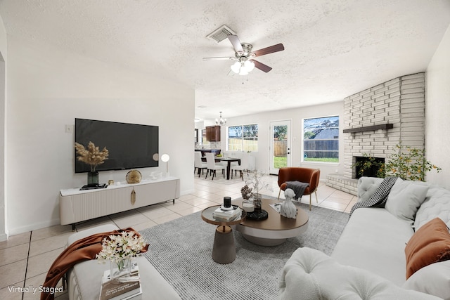 tiled living room featuring a fireplace, a textured ceiling, and ceiling fan with notable chandelier