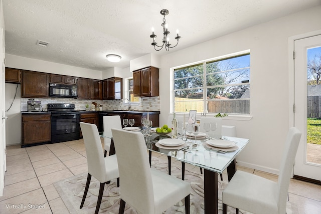 tiled dining space with a textured ceiling, a notable chandelier, and sink