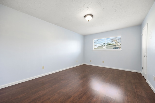 spare room featuring dark hardwood / wood-style floors and a textured ceiling