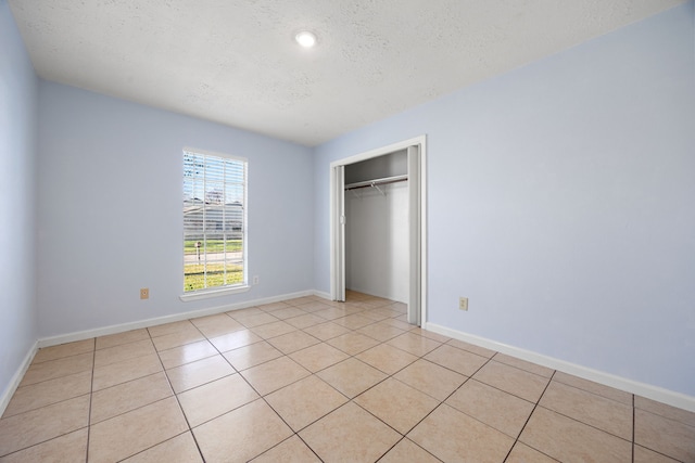 unfurnished bedroom with light tile patterned floors, a textured ceiling, and a closet