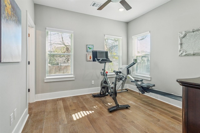 workout area featuring visible vents, a healthy amount of sunlight, baseboards, and wood finished floors