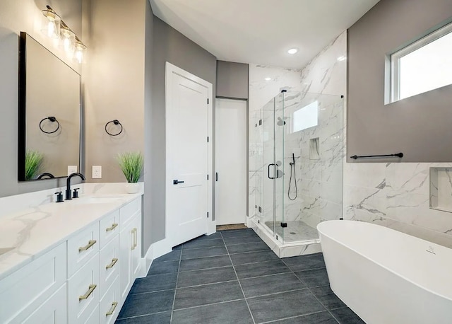 bathroom featuring a marble finish shower, tile patterned flooring, tile walls, a freestanding bath, and vanity