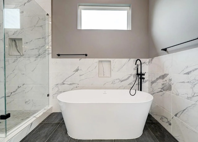 bathroom with a stall shower, tile walls, and a freestanding tub