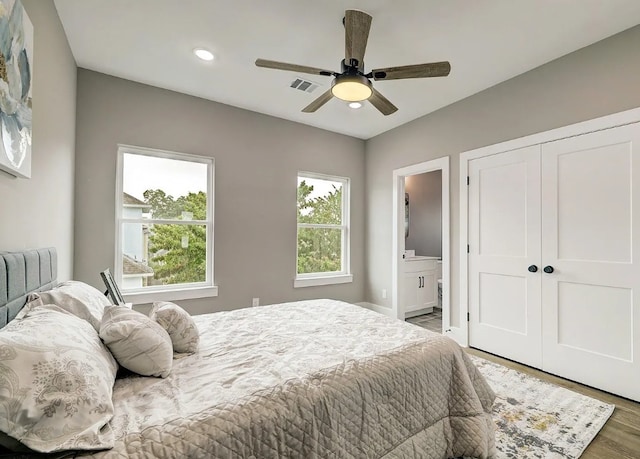 bedroom featuring visible vents, ensuite bathroom, wood finished floors, a closet, and a ceiling fan