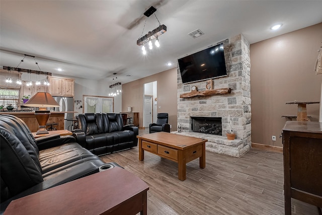 living room featuring a notable chandelier, light hardwood / wood-style floors, and a fireplace