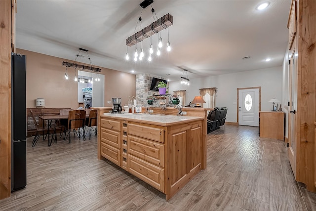 kitchen featuring a kitchen island with sink, black refrigerator, and pendant lighting