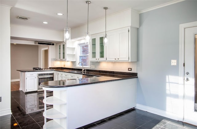 kitchen with kitchen peninsula, pendant lighting, white cabinets, dark tile patterned flooring, and appliances with stainless steel finishes