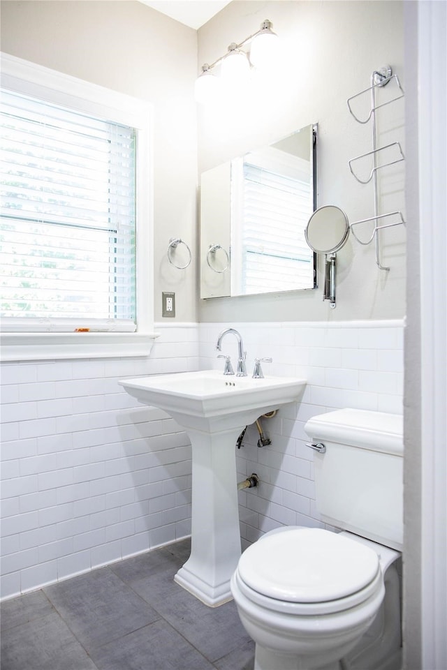 bathroom featuring tile patterned floors, toilet, and tile walls