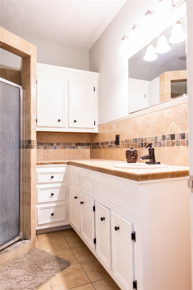 bathroom with decorative backsplash, a textured ceiling, vanity, tile patterned flooring, and a shower with shower door