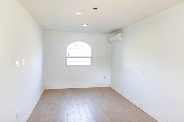 empty room with a wall unit AC and light hardwood / wood-style flooring