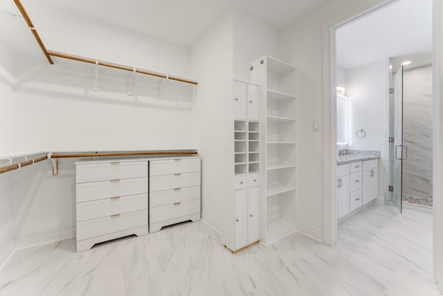 spacious closet with marble finish floor and a sink