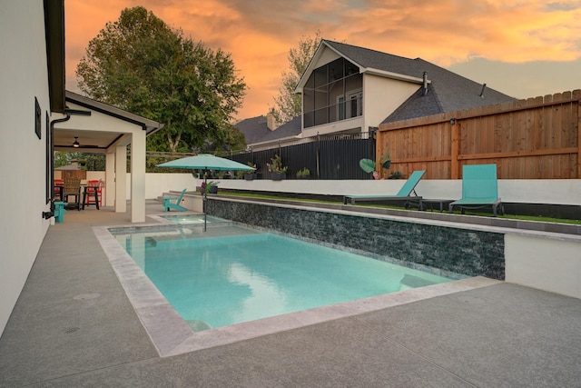 pool at dusk featuring a bar and a patio area