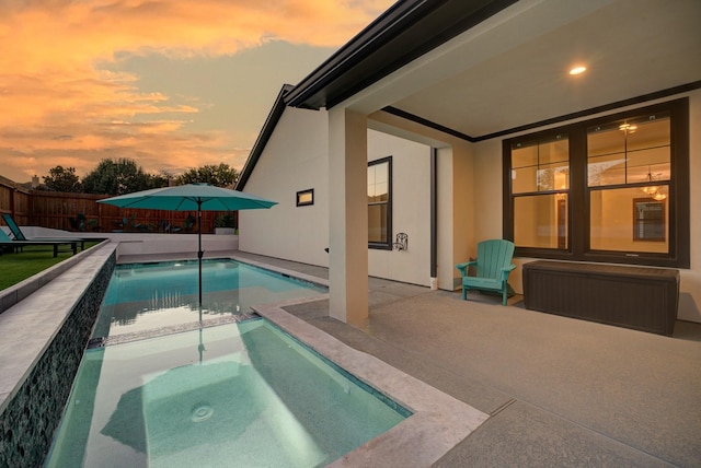 pool at dusk featuring a patio area and an in ground hot tub