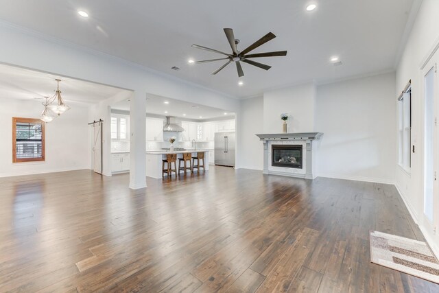 unfurnished living room featuring ceiling fan, dark hardwood / wood-style floors, sink, and crown molding