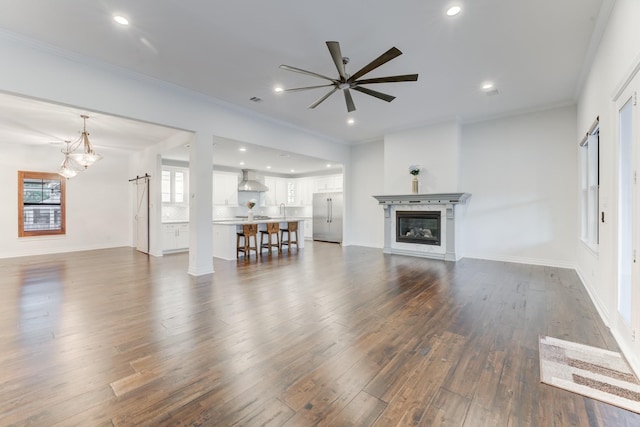 unfurnished living room with crown molding, a glass covered fireplace, dark wood finished floors, and recessed lighting