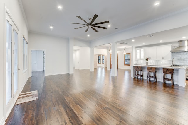 unfurnished living room featuring ceiling fan, dark hardwood / wood-style flooring, and ornamental molding