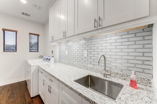 clothes washing area featuring cabinets, dark hardwood / wood-style flooring, washing machine and clothes dryer, and sink