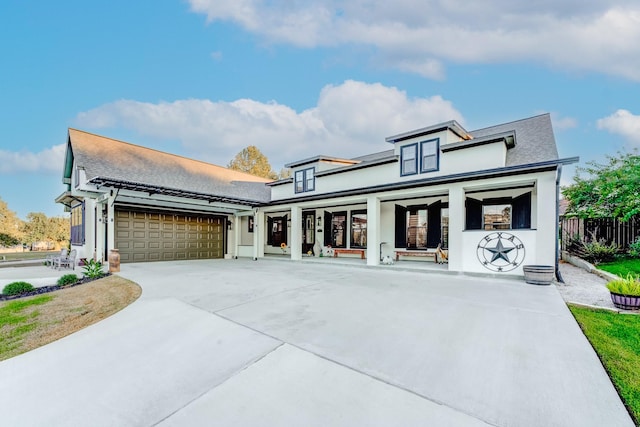 view of front facade with concrete driveway, an attached garage, fence, and stucco siding