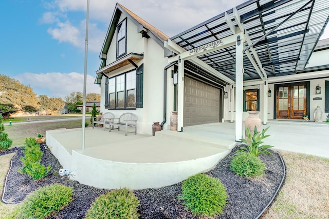 exterior space featuring french doors, concrete driveway, an attached garage, and stucco siding