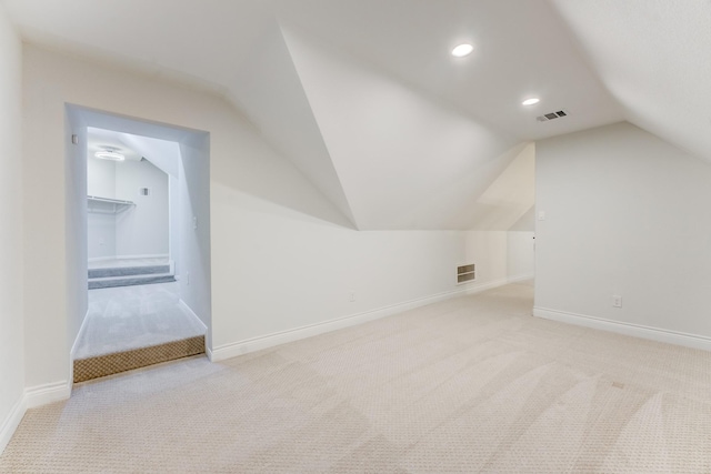 additional living space featuring light colored carpet and vaulted ceiling