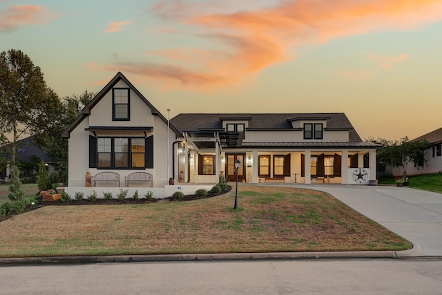 modern inspired farmhouse featuring metal roof, a front lawn, a standing seam roof, and concrete driveway