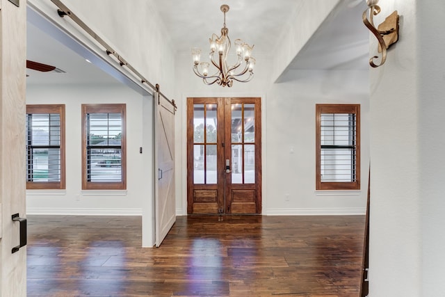 entryway featuring dark hardwood / wood-style floors, an inviting chandelier, french doors, and a barn door