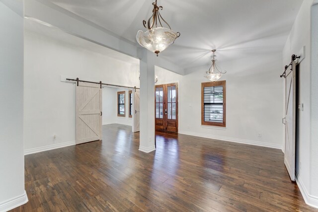 unfurnished room with french doors, a barn door, and dark hardwood / wood-style floors